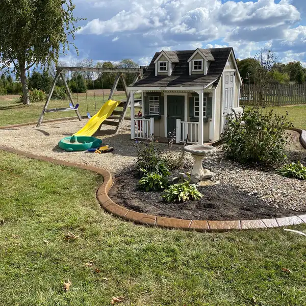 Curbed play area and a curved rock flower bed in a backyard
